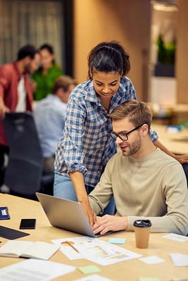 two people working together at a laptop in a casual office