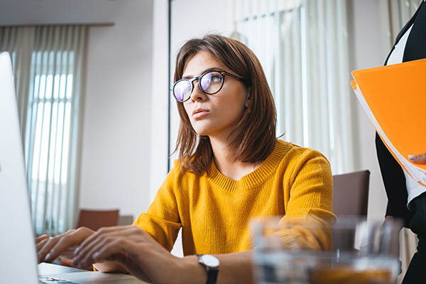 Woman working in an office with a yellow sweater